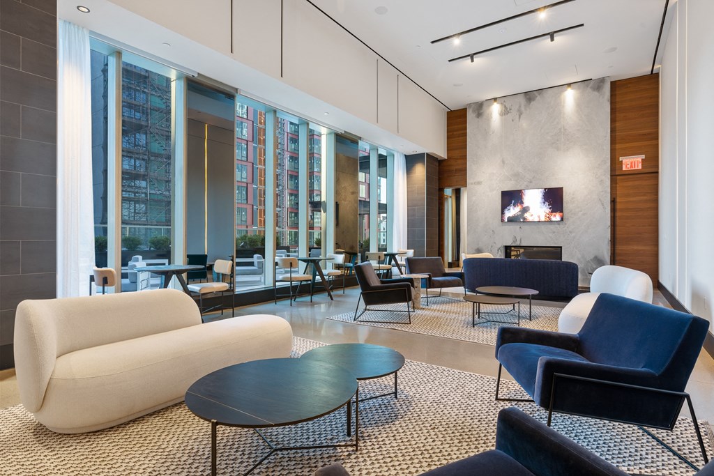 a lounge area with couches chairs and tables and a television at The Paxton, Brooklyn, NY